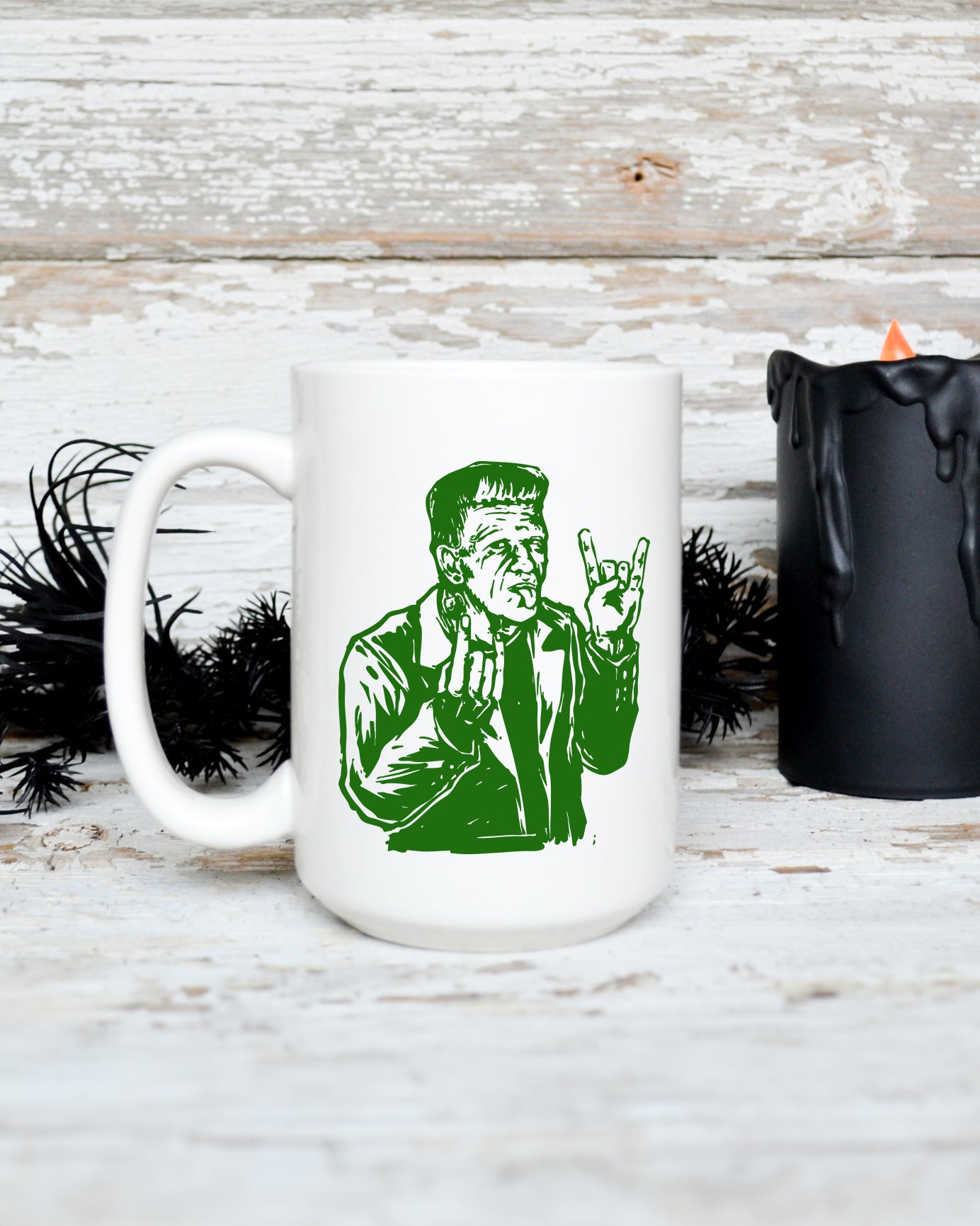 15 oz white ceramic mug featuring a green Frankenstein monster making a rock hand gesture in vintage horror-inspired artwork.
