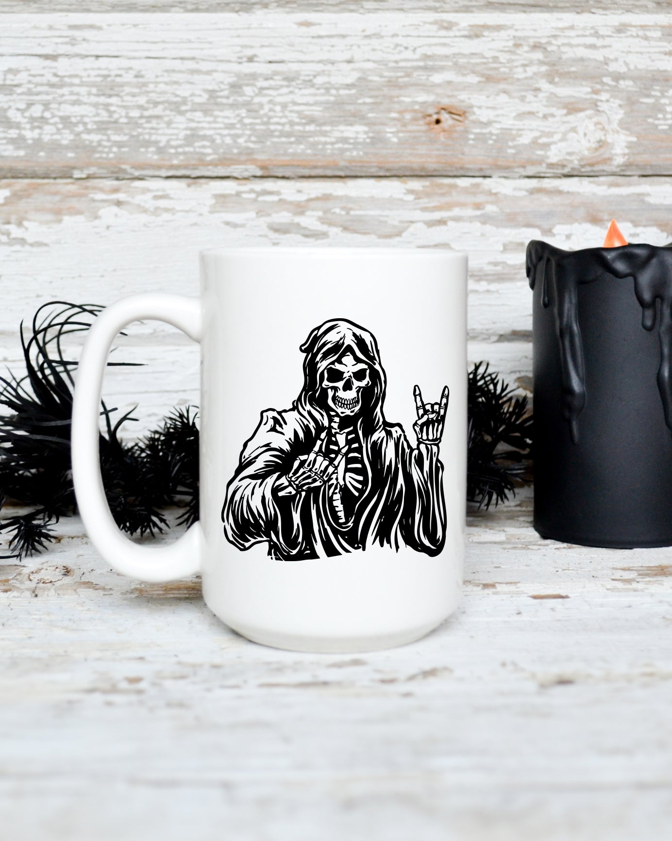 15 oz white ceramic mug featuring a hooded skeleton reaper making a rock hand gesture in black gothic-style artwork.